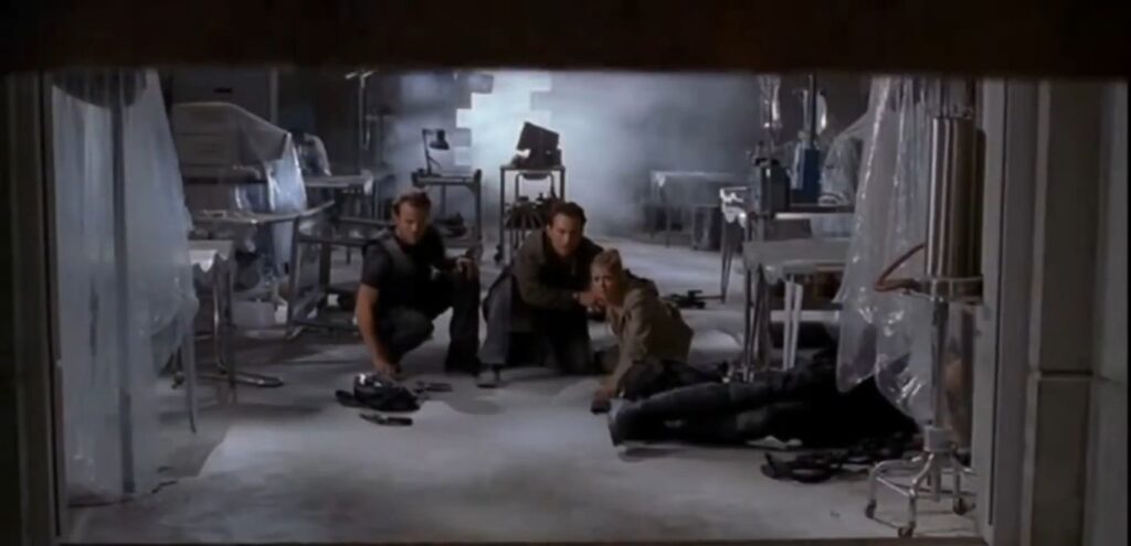 Three characters, including Christian Slater and Tara Reid, crouch in a smoke-filled laboratory in a scene from the video game adaptation Alone in the Dark.