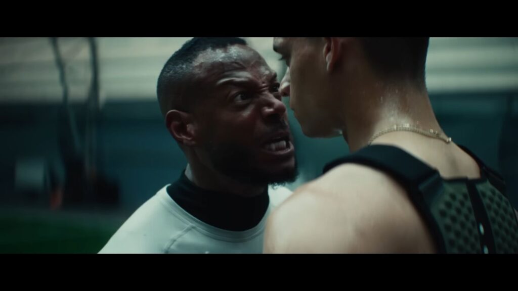 An intense confrontation scene from the sports horror movie Him (2025) showing Marlon Wayans furiously shouting inches away from another man's face.