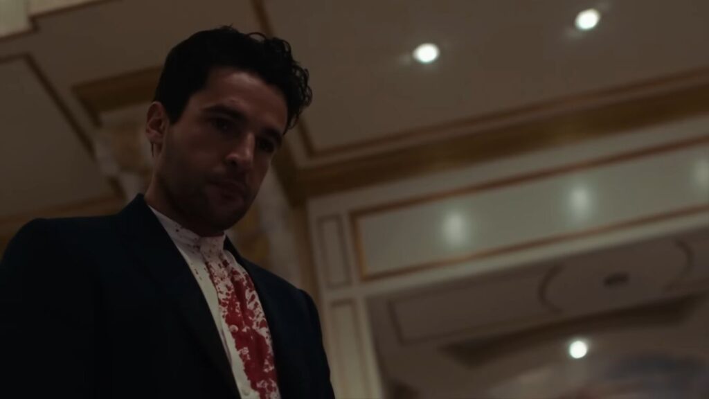 Christopher Abbott wearing a dark suit jacket and a white dress shirt soaked in blood looking downward in Possessor.